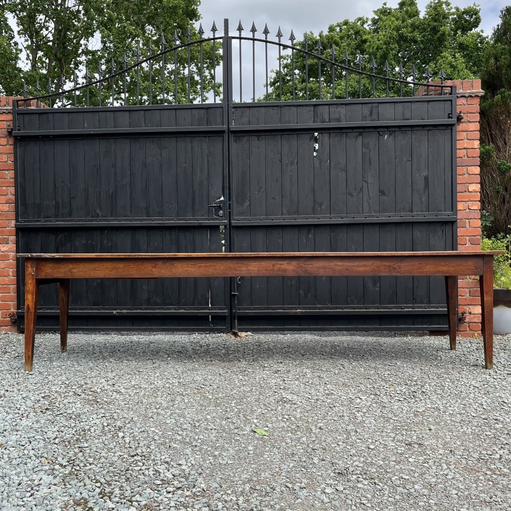 An exceptionally long 19th-century French cherrywood farmhouse table featuring a flat wooden top, straight aprons, and four square tapered legs.