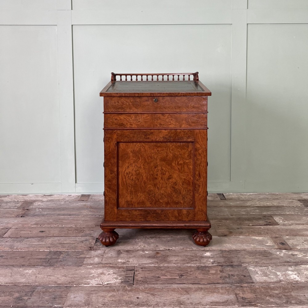 A 19th-century burr walnut Davenport desk featuring a sloped writing lid with a spindled gallery rail, side drawers, and turned feet. View II