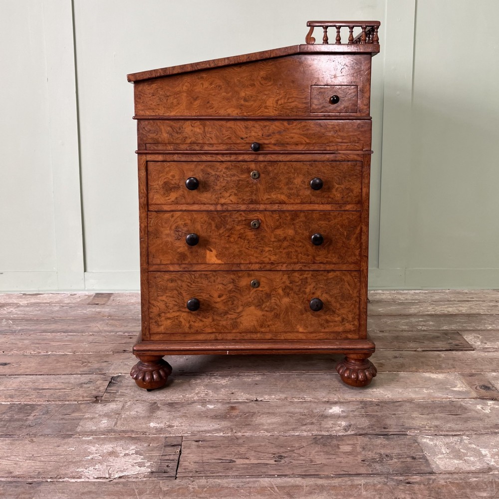 A 19th-century burr walnut Davenport desk featuring a sloped writing lid with a spindled gallery rail, side drawers, and turned feet. View VII