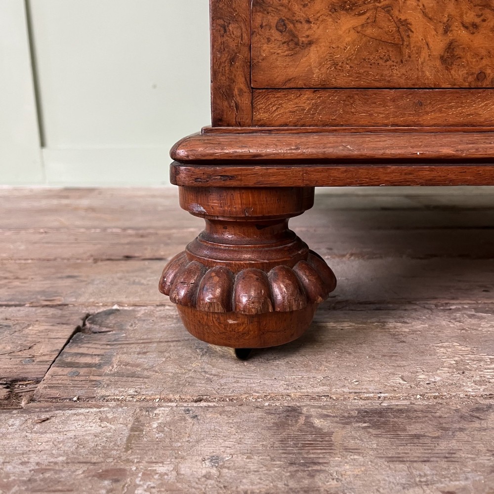 A 19th-century burr walnut Davenport desk featuring a sloped writing lid with a spindled gallery rail, side drawers, and turned feet. View IX