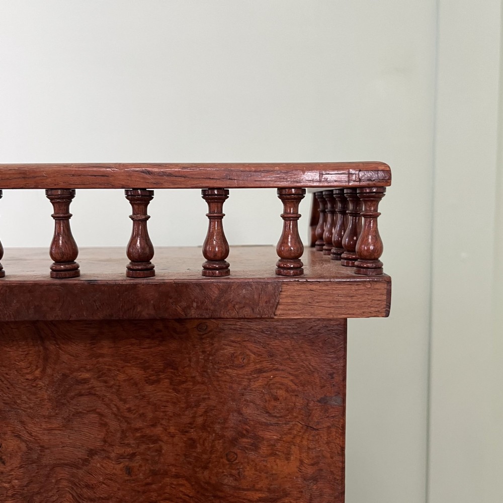 A 19th-century burr walnut Davenport desk featuring a sloped writing lid with a spindled gallery rail, side drawers, and turned feet. View XI