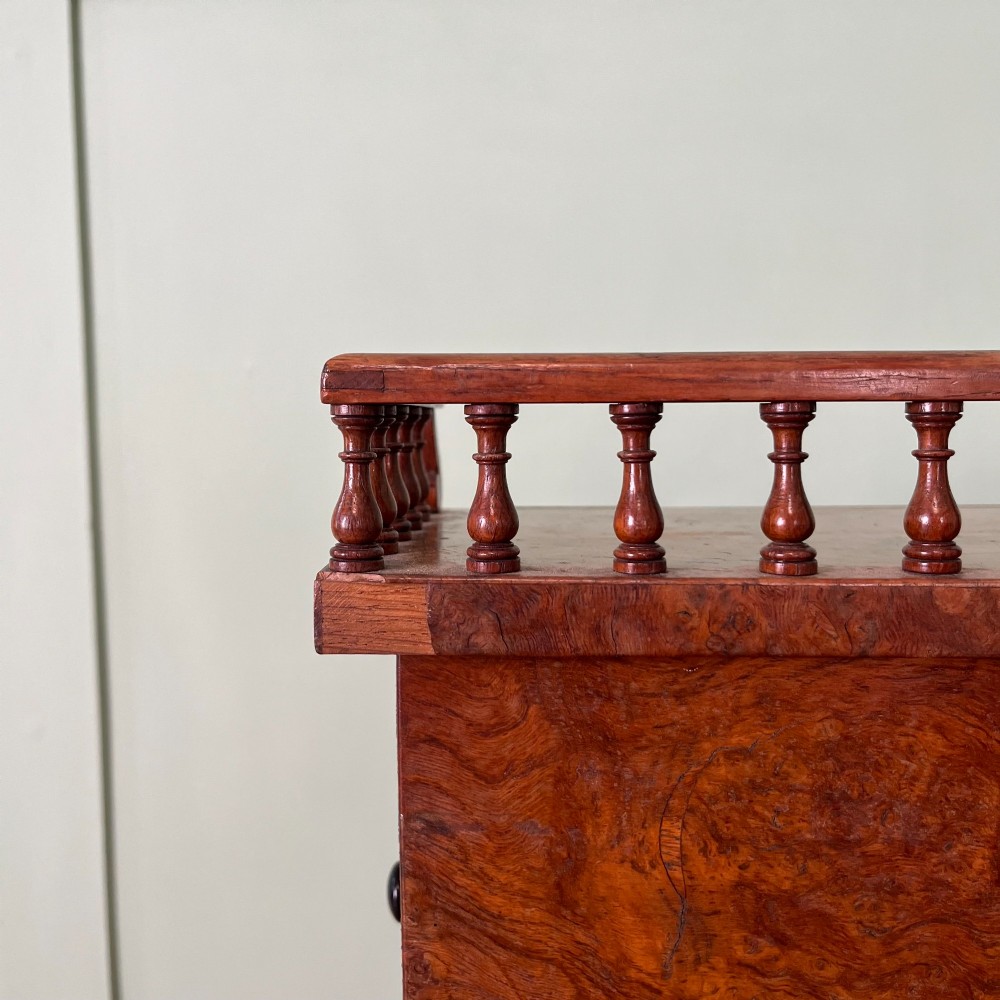 A 19th-century burr walnut Davenport desk featuring a sloped writing lid with a spindled gallery rail, side drawers, and turned feet. View XII
