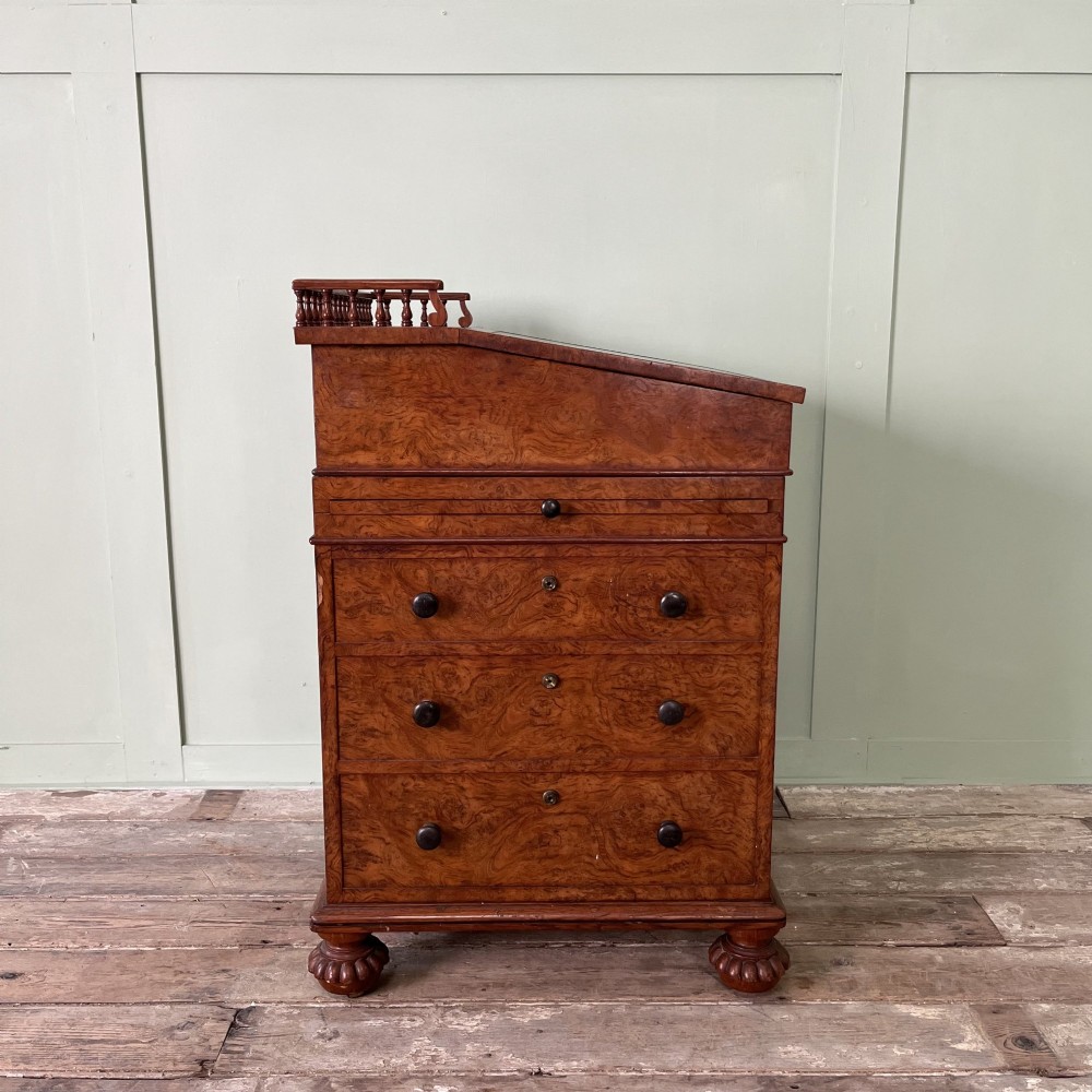 A 19th-century burr walnut Davenport desk featuring a sloped writing lid with a spindled gallery rail, side drawers, and turned feet. View XIII