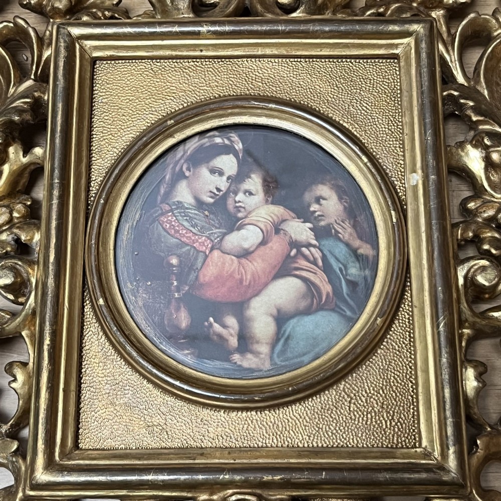A 19th-century Florentine carved giltwood picture frame featuring openwork acanthus leaves, scrollwork cresting, and a central circular image of the Madonna and Child. View II