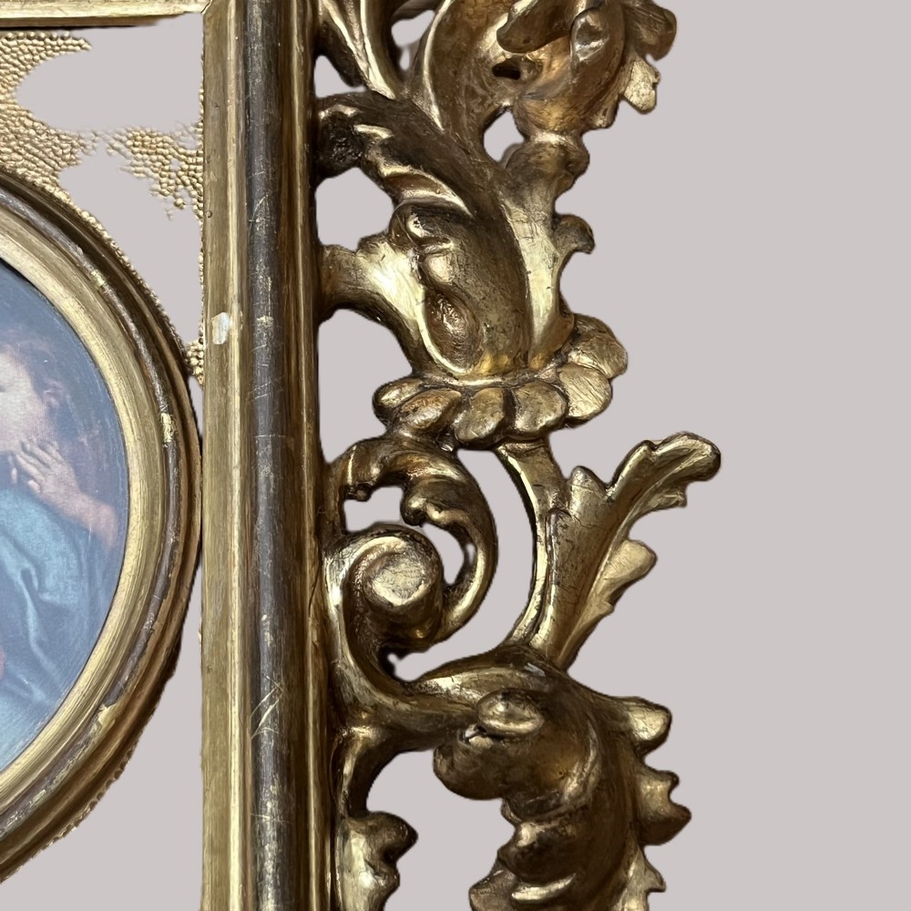 A 19th-century Florentine carved giltwood picture frame featuring openwork acanthus leaves, scrollwork cresting, and a central circular image of the Madonna and Child. View V