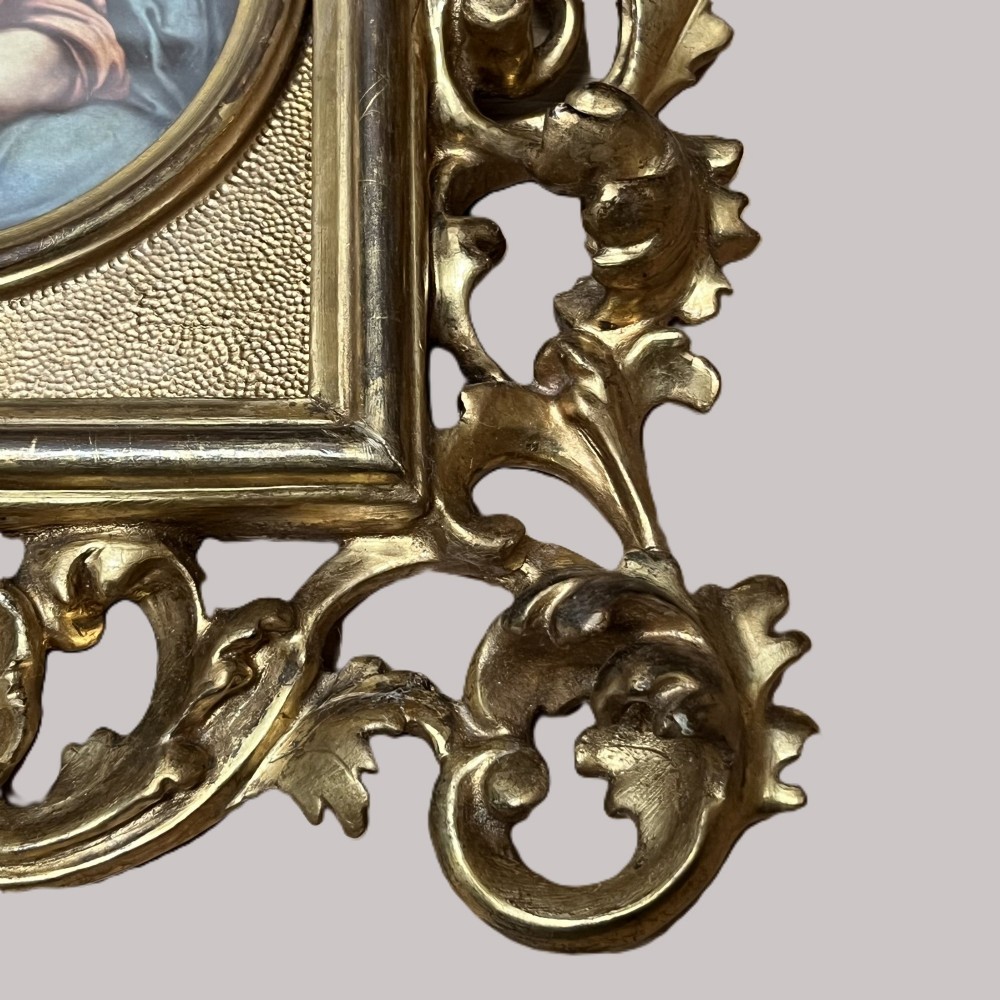 A 19th-century Florentine carved giltwood picture frame featuring openwork acanthus leaves, scrollwork cresting, and a central circular image of the Madonna and Child. View VI