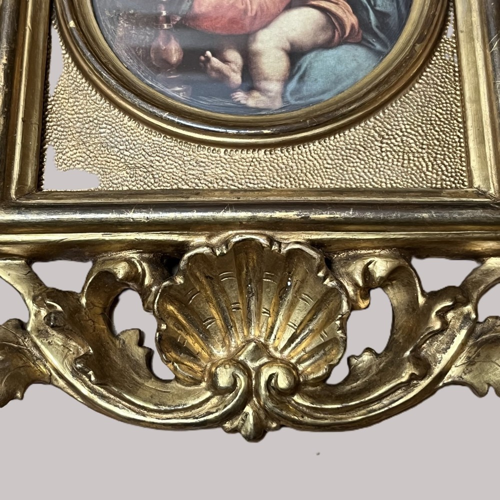 A 19th-century Florentine carved giltwood picture frame featuring openwork acanthus leaves, scrollwork cresting, and a central circular image of the Madonna and Child. View VII
