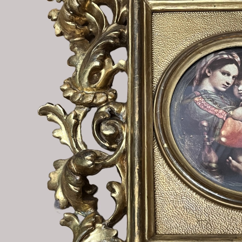 A 19th-century Florentine carved giltwood picture frame featuring openwork acanthus leaves, scrollwork cresting, and a central circular image of the Madonna and Child. View IX