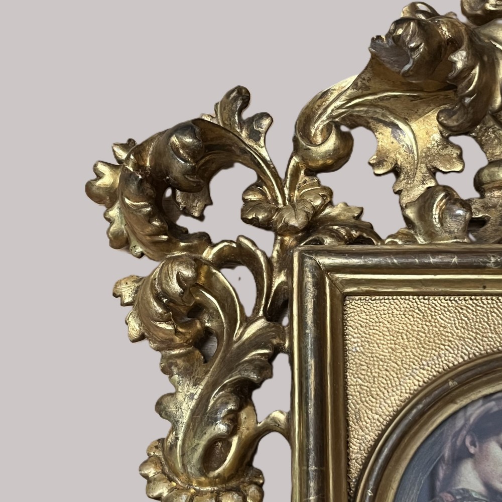 A 19th-century Florentine carved giltwood picture frame featuring openwork acanthus leaves, scrollwork cresting, and a central circular image of the Madonna and Child. View X