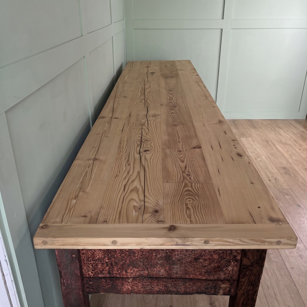 An early 19th-century pine serving table featuring a natural scrubbed timber top and a dark painted base with six legs and four drawers. View V