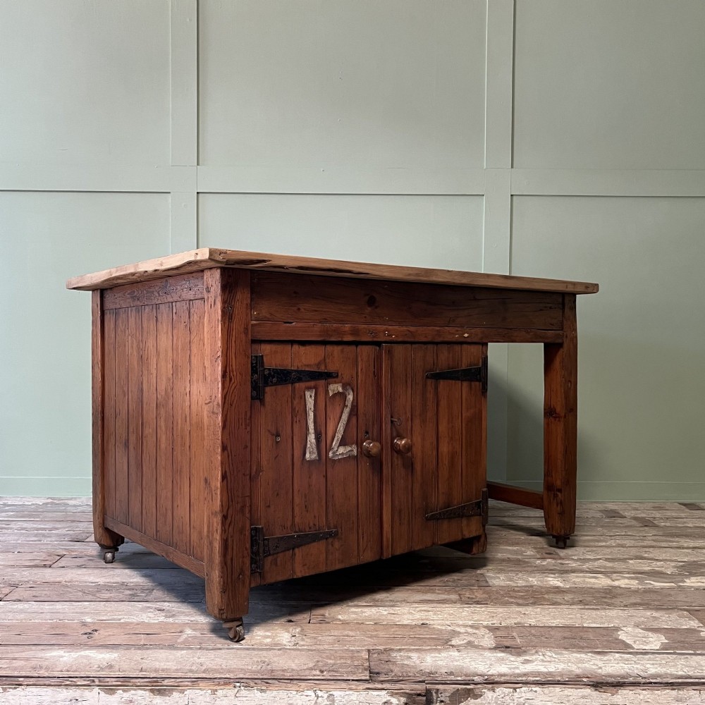 An early twentieth-century rustic pine bakers prep table with dual cupboard doors, black iron strap hinges, painted number twelve, and wooden castors. View IV