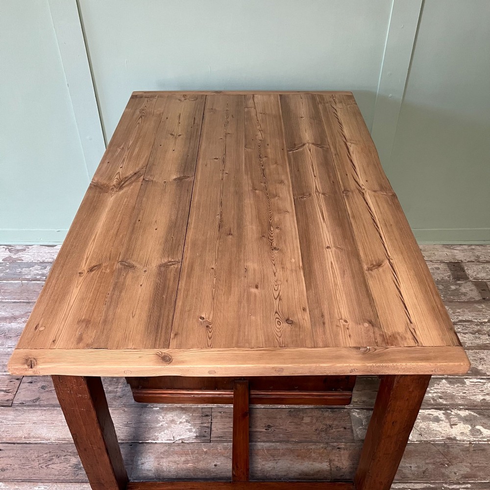 An early twentieth-century rustic pine bakers prep table with dual cupboard doors, black iron strap hinges, painted number twelve, and wooden castors. View VIII
