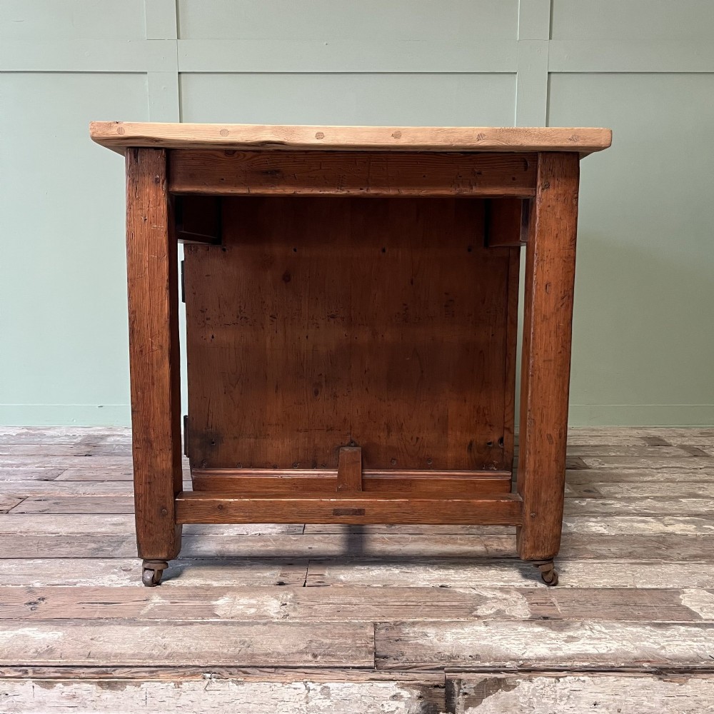 An early twentieth-century rustic pine bakers prep table with dual cupboard doors, black iron strap hinges, painted number twelve, and wooden castors. View IX