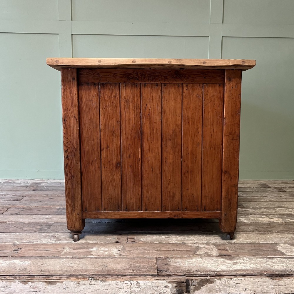 An early twentieth-century rustic pine bakers prep table with dual cupboard doors, black iron strap hinges, painted number twelve, and wooden castors. View XI