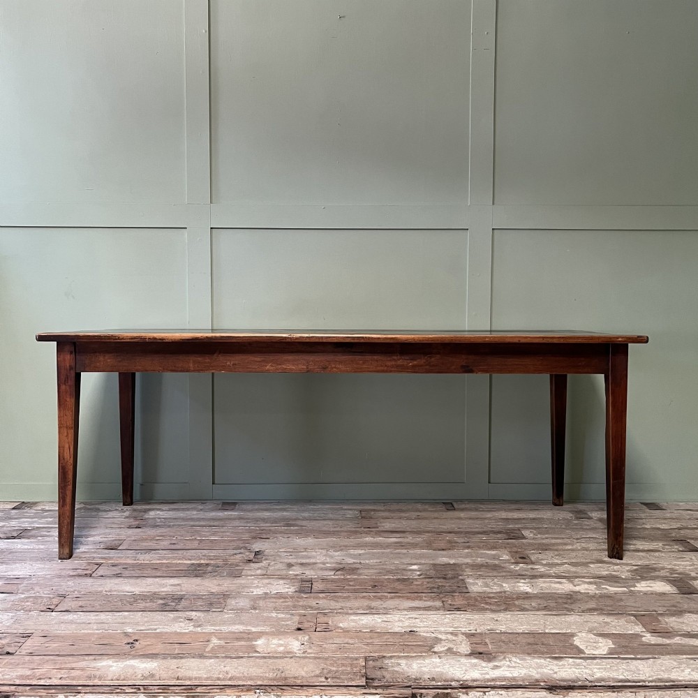 A nineteenth-century French cherrywood farmhouse dining table featuring tapered square legs and a rectangular plank top.