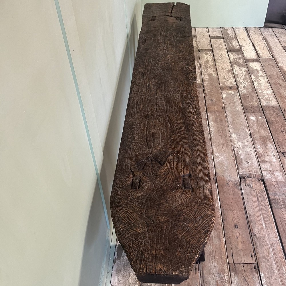 A long rustic dark oak bench featuring an unrefined thick slab seat supported by four simple splayed legs. View VI