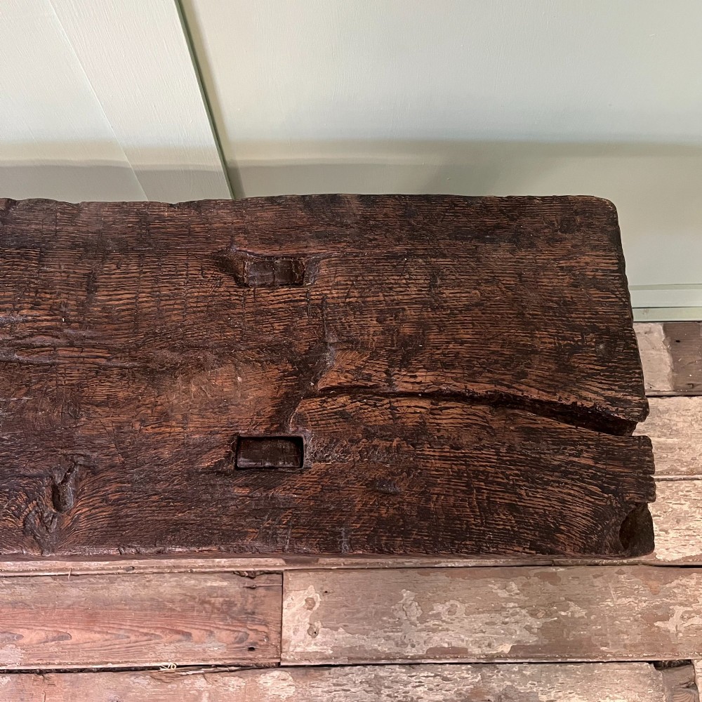 A long rustic dark oak bench featuring an unrefined thick slab seat supported by four simple splayed legs. View IX