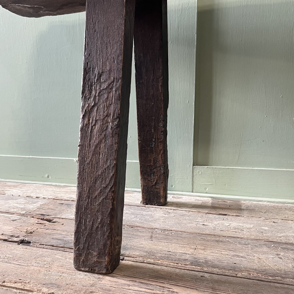 A long rustic dark oak bench featuring an unrefined thick slab seat supported by four simple splayed legs. View XIII