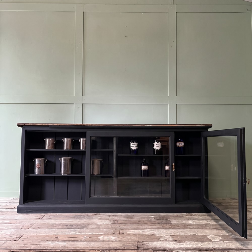 A Victorian shop counter featuring a dark painted pine base with two large glass panel doors and a polished mahogany top surface. View II