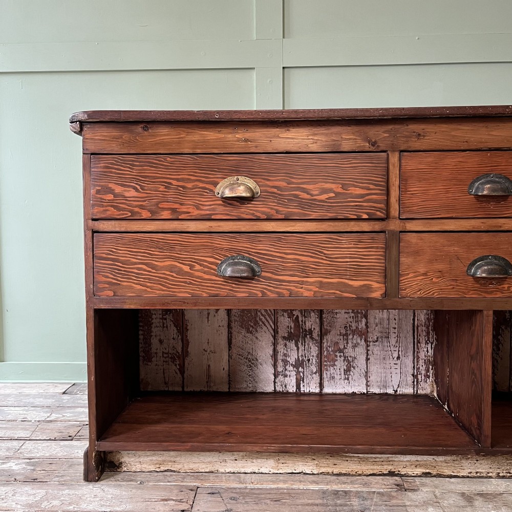A Victorian shop counter featuring a dark painted pine base with two large glass panel doors and a polished mahogany top surface. View V