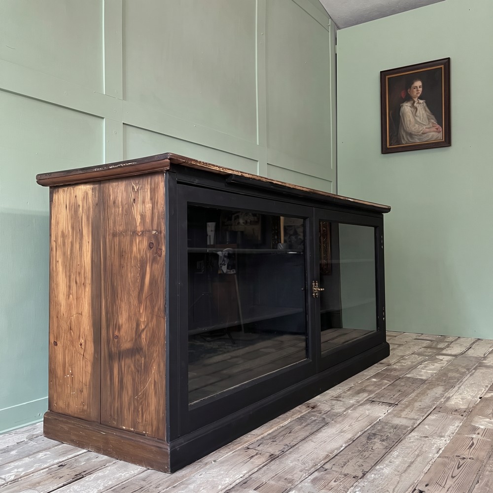 A Victorian shop counter featuring a dark painted pine base with two large glass panel doors and a polished mahogany top surface. View VIII