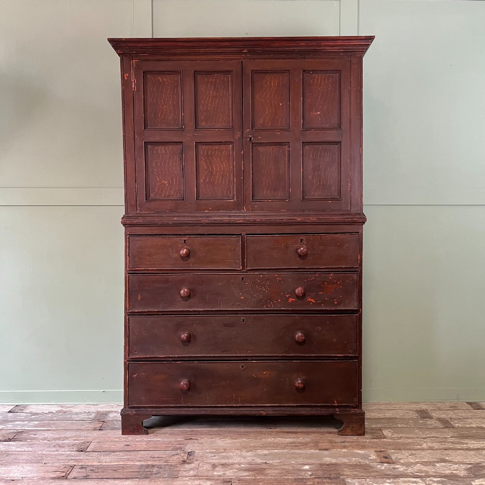 An early 19th-century Irish painted pine press cupboard with two panelled upper doors over a base section containing five drawers.