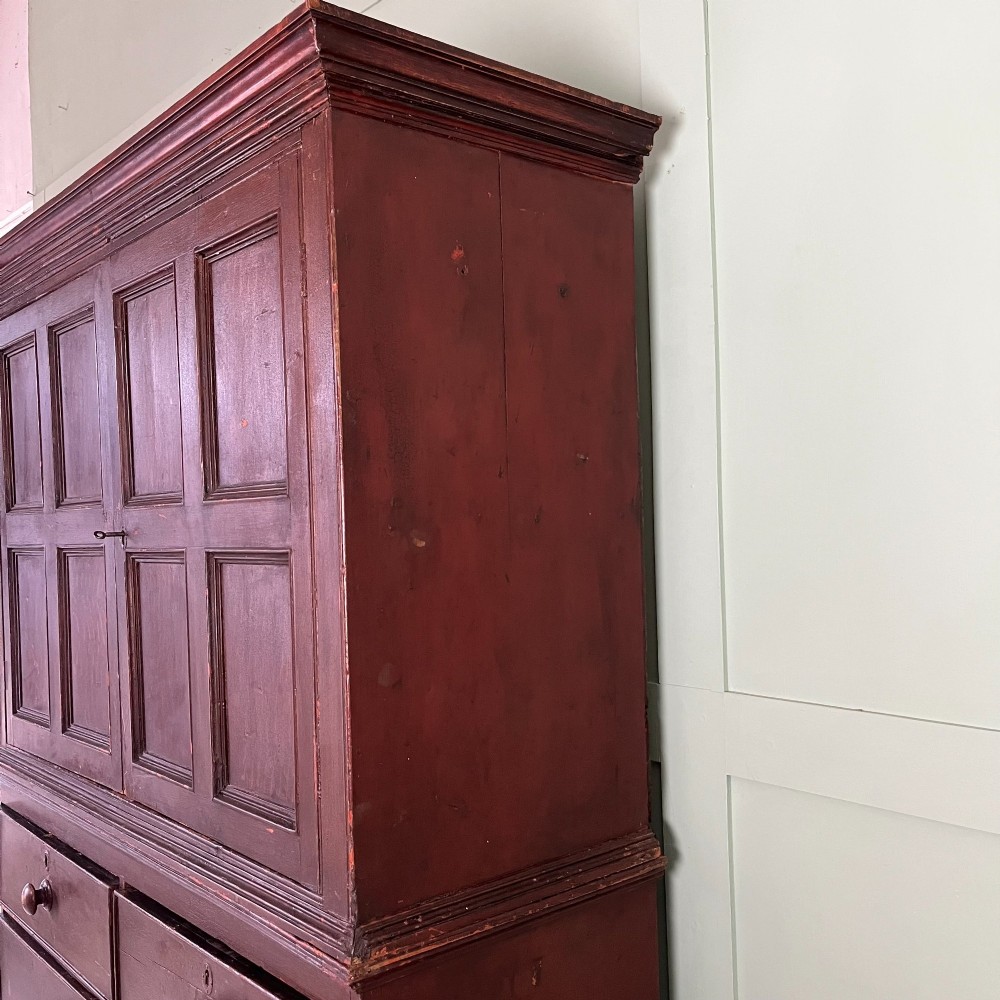 An early 19th-century Irish painted pine press cupboard with two panelled upper doors over a base section containing five drawers. View X