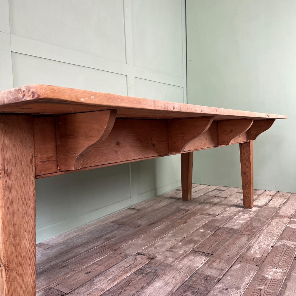 A large Victorian pine farmhouse dining table featuring a multi-plank top, deep apron with supporting brackets, and four straight tapered legs. View V