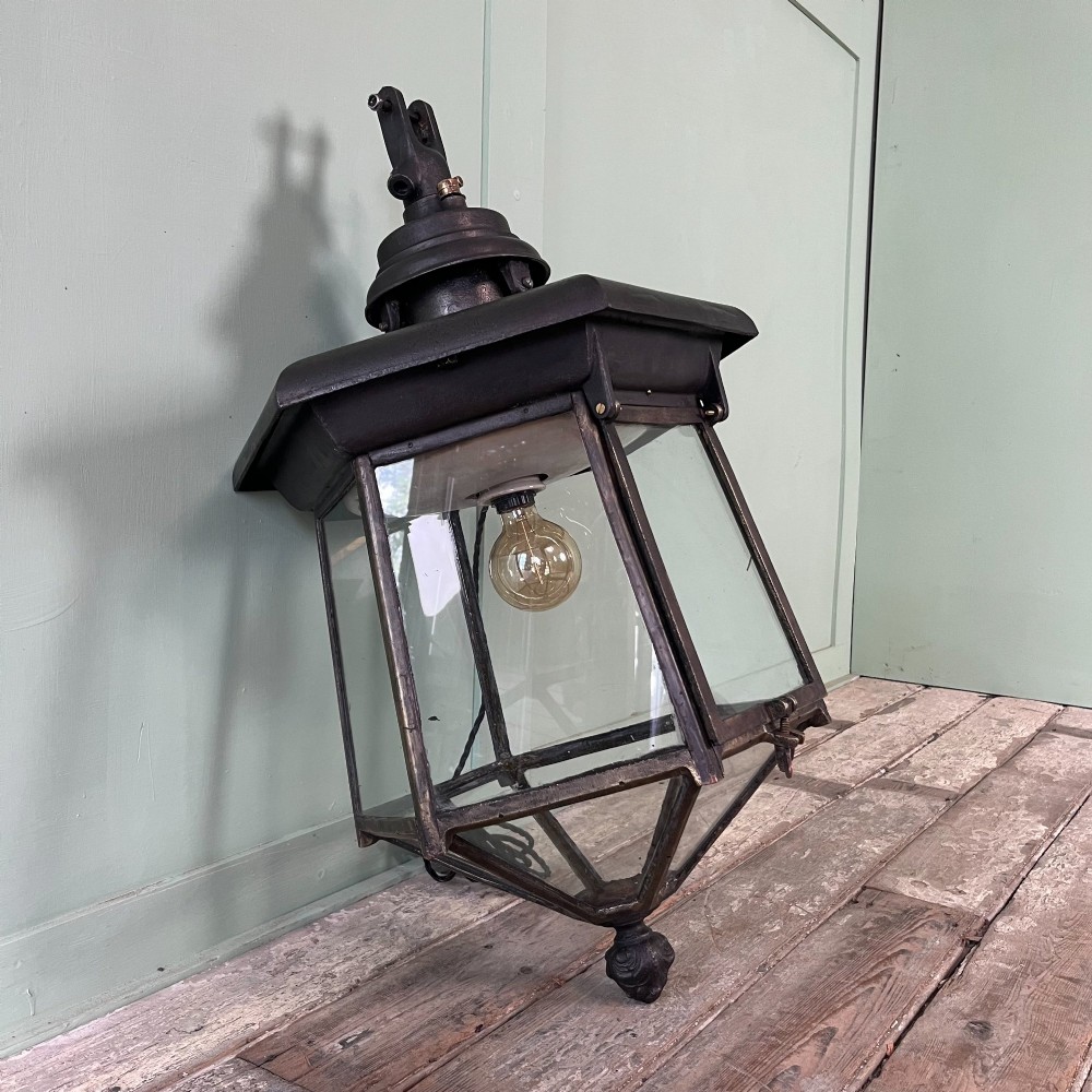A pair of large metal street lanterns with glazed glass panels alongside two large decorative scrolled wrought iron wall brackets. View V