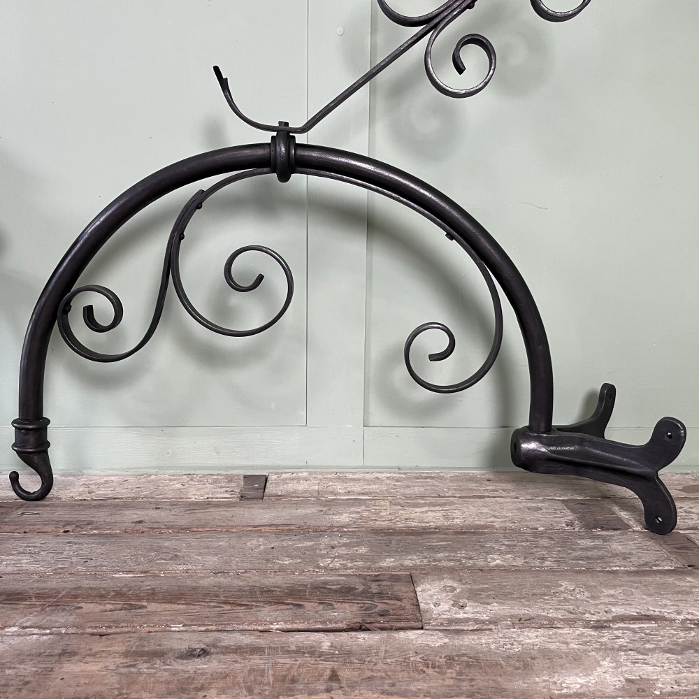 A pair of large metal street lanterns with glazed glass panels alongside two large decorative scrolled wrought iron wall brackets. View VII