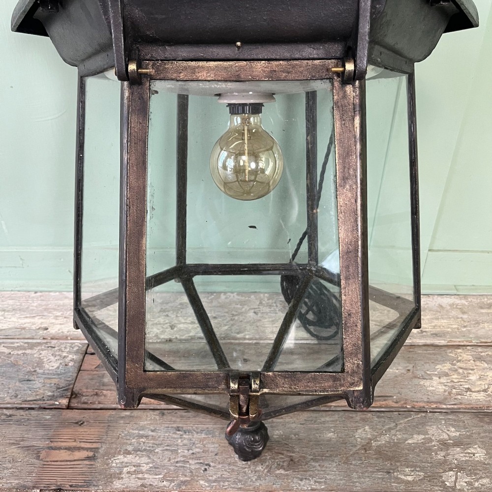 A pair of large metal street lanterns with glazed glass panels alongside two large decorative scrolled wrought iron wall brackets. View VIII