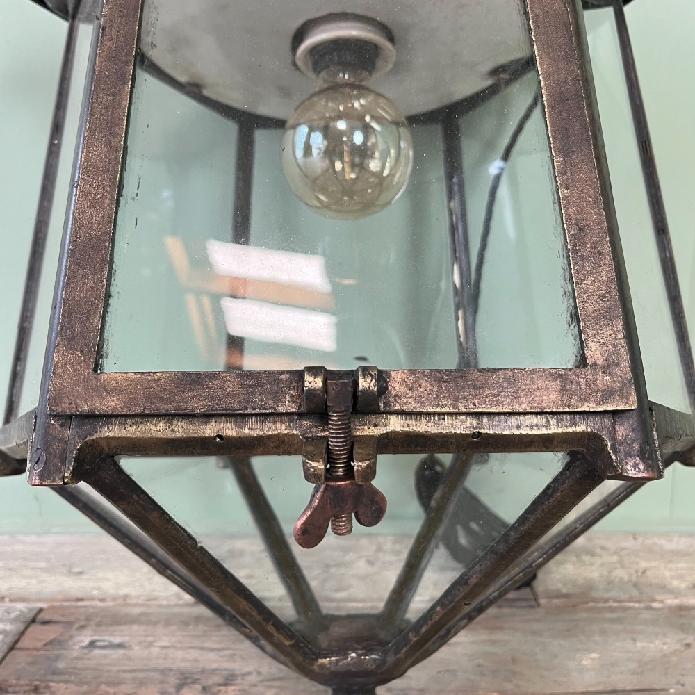 A pair of large metal street lanterns with glazed glass panels alongside two large decorative scrolled wrought iron wall brackets. View IX