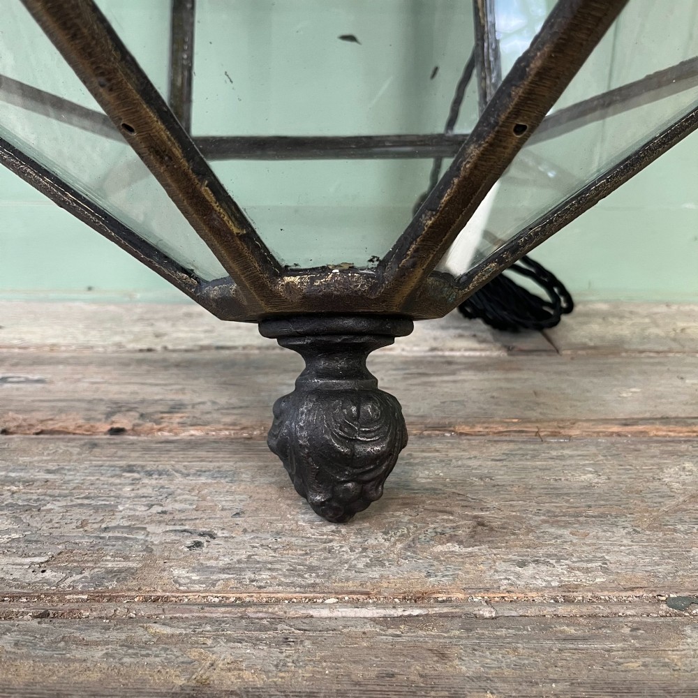A pair of large metal street lanterns with glazed glass panels alongside two large decorative scrolled wrought iron wall brackets. View X