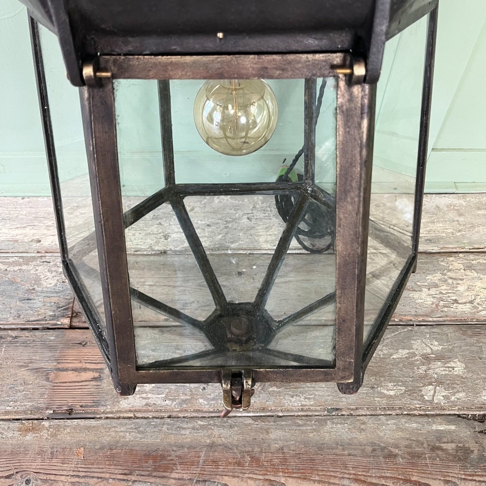 A pair of large metal street lanterns with glazed glass panels alongside two large decorative scrolled wrought iron wall brackets. View XI