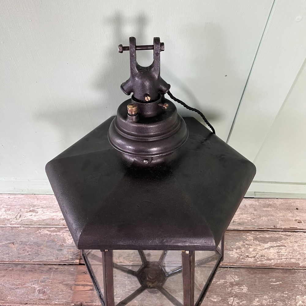 A pair of large metal street lanterns with glazed glass panels alongside two large decorative scrolled wrought iron wall brackets. View XIII