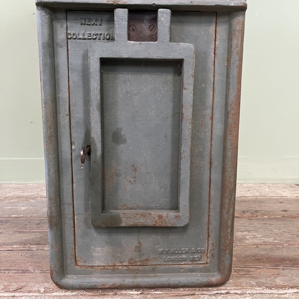 A cast iron George VI post box with a raised GR Royal cypher alongside a tall matching metal pedestal stand. View VI