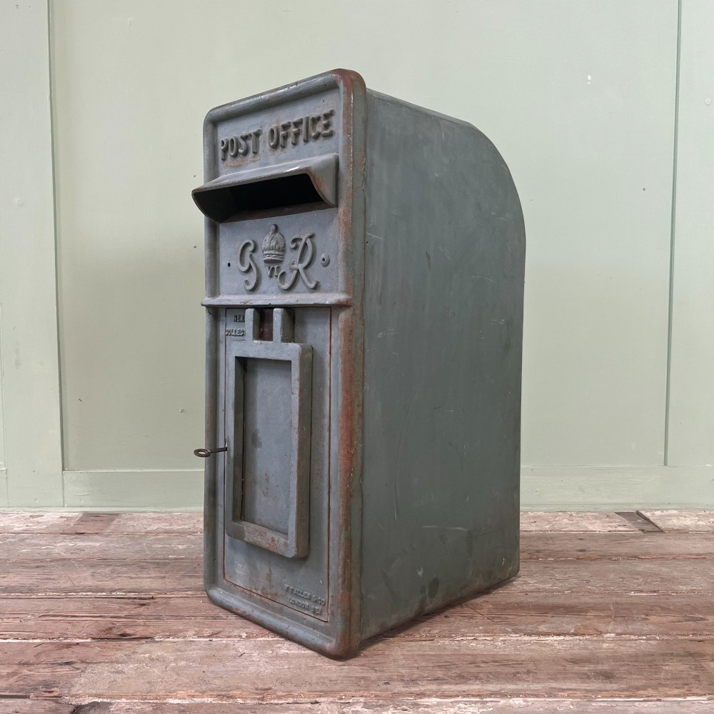 A cast iron George VI post box with a raised GR Royal cypher alongside a tall matching metal pedestal stand. View X