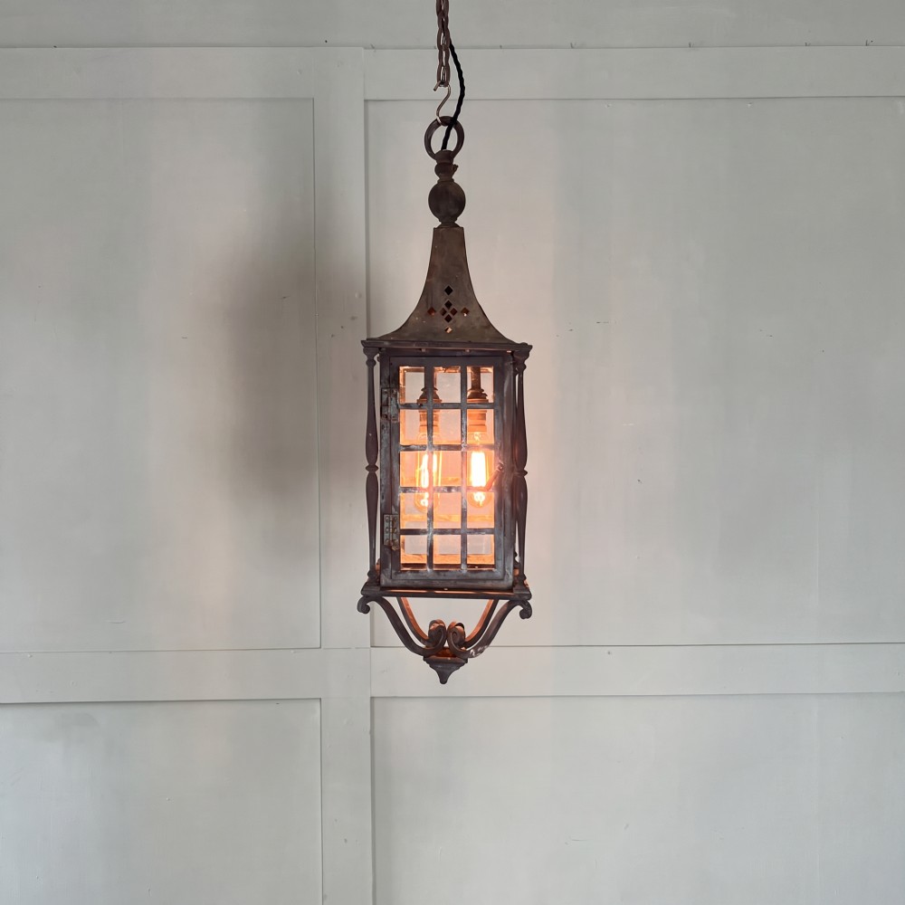 An Edwardian rectangular brass hanging lantern light fixture with glazed window panels, internal bulb fittings, a pagoda top, and a lower scroll finial. View II