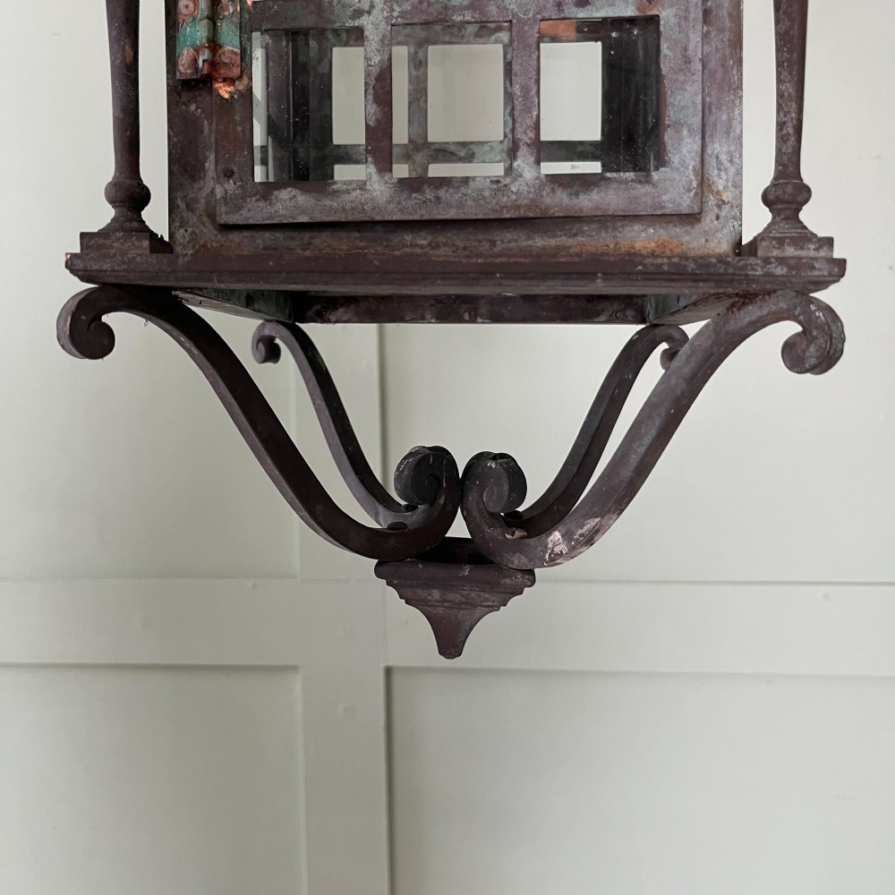 An Edwardian rectangular brass hanging lantern light fixture with glazed window panels, internal bulb fittings, a pagoda top, and a lower scroll finial. View IV