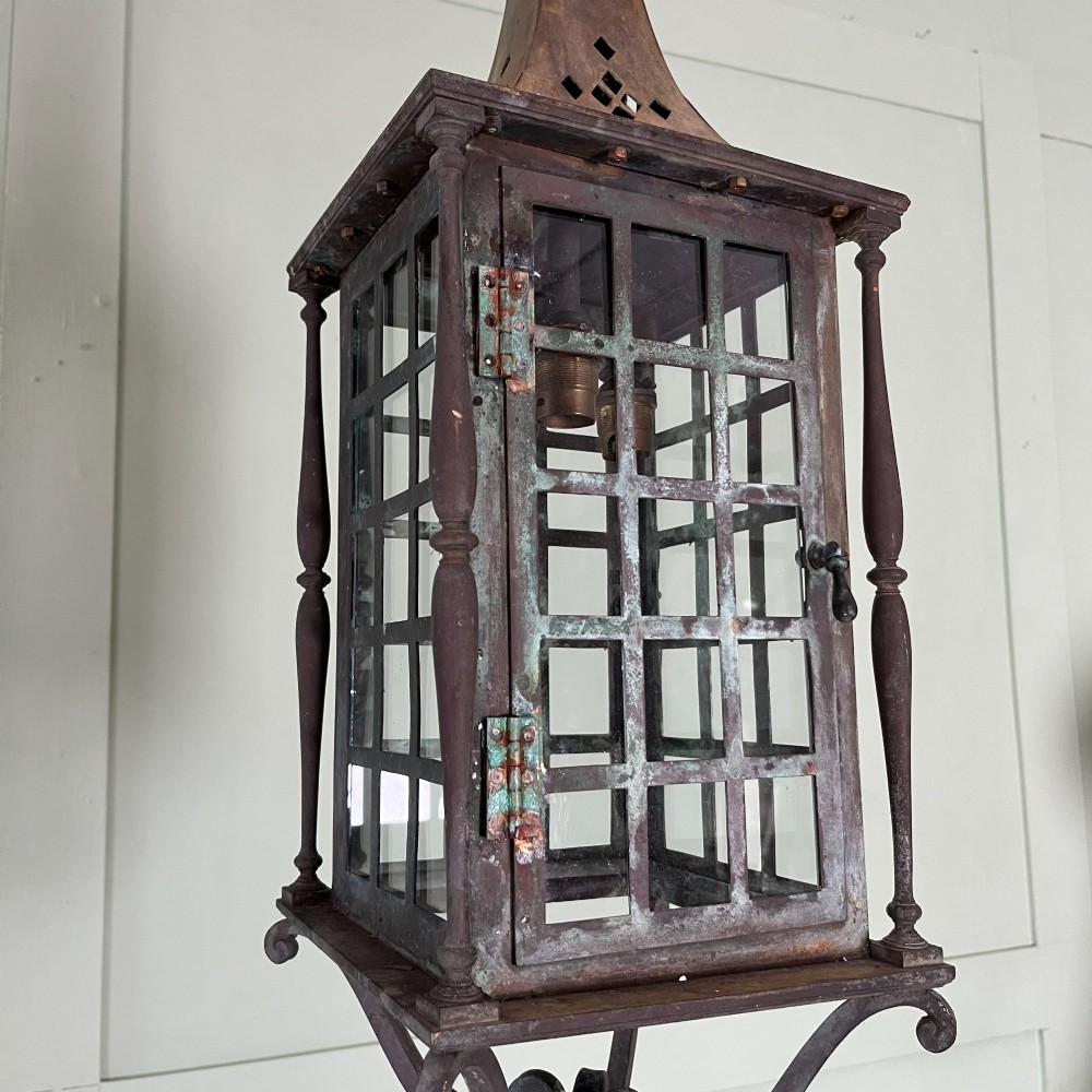An Edwardian rectangular brass hanging lantern light fixture with glazed window panels, internal bulb fittings, a pagoda top, and a lower scroll finial. View V
