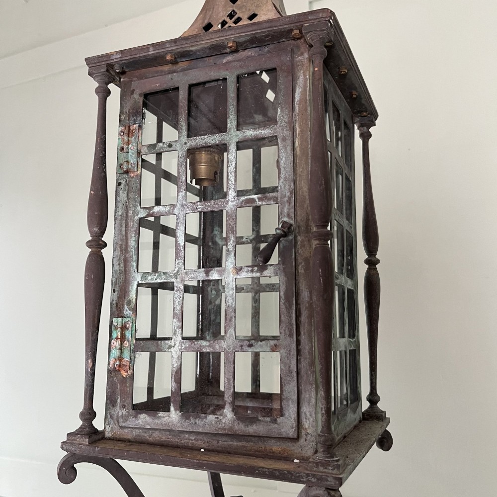 An Edwardian rectangular brass hanging lantern light fixture with glazed window panels, internal bulb fittings, a pagoda top, and a lower scroll finial. View VI