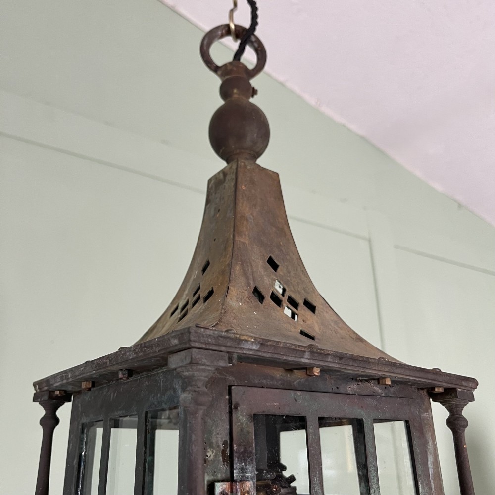 An Edwardian rectangular brass hanging lantern light fixture with glazed window panels, internal bulb fittings, a pagoda top, and a lower scroll finial. View VII