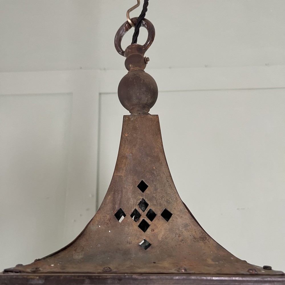 An Edwardian rectangular brass hanging lantern light fixture with glazed window panels, internal bulb fittings, a pagoda top, and a lower scroll finial. View IX