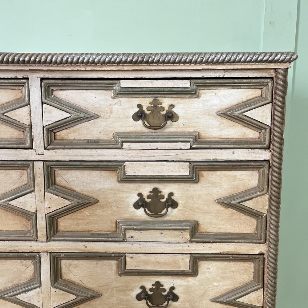 An Edwardian painted chest of drawers featuring eight drawer fronts decorated with geometric panel mouldings, drop handles, and rope-twist edge detailing. View III