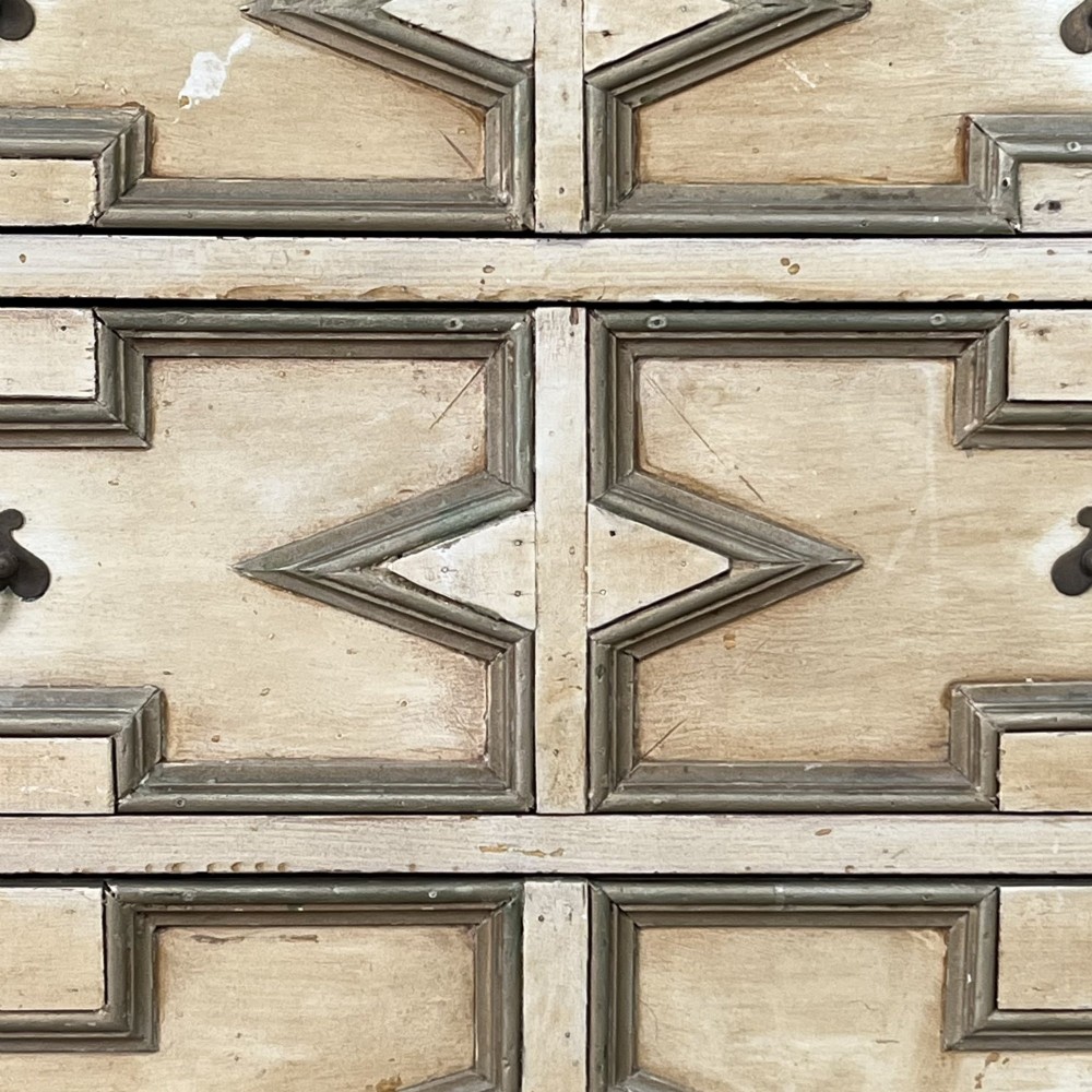 An Edwardian painted chest of drawers featuring eight drawer fronts decorated with geometric panel mouldings, drop handles, and rope-twist edge detailing. View V