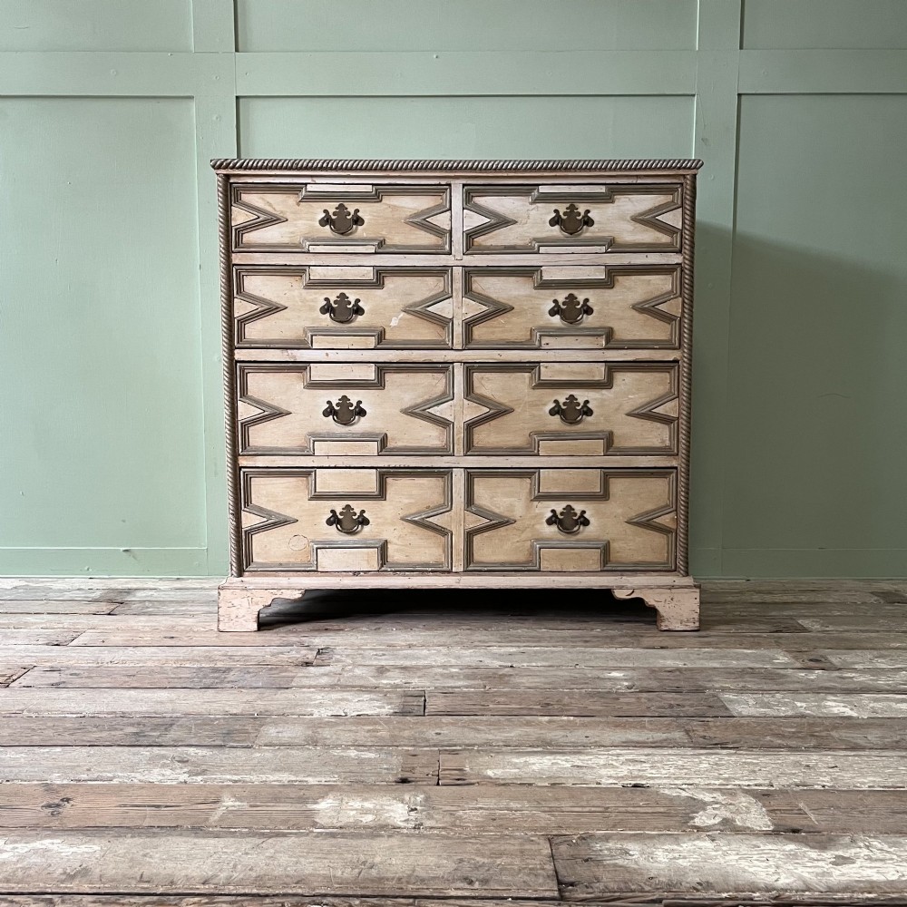 An Edwardian painted chest of drawers featuring eight drawer fronts decorated with geometric panel mouldings, drop handles, and rope-twist edge detailing. View VII