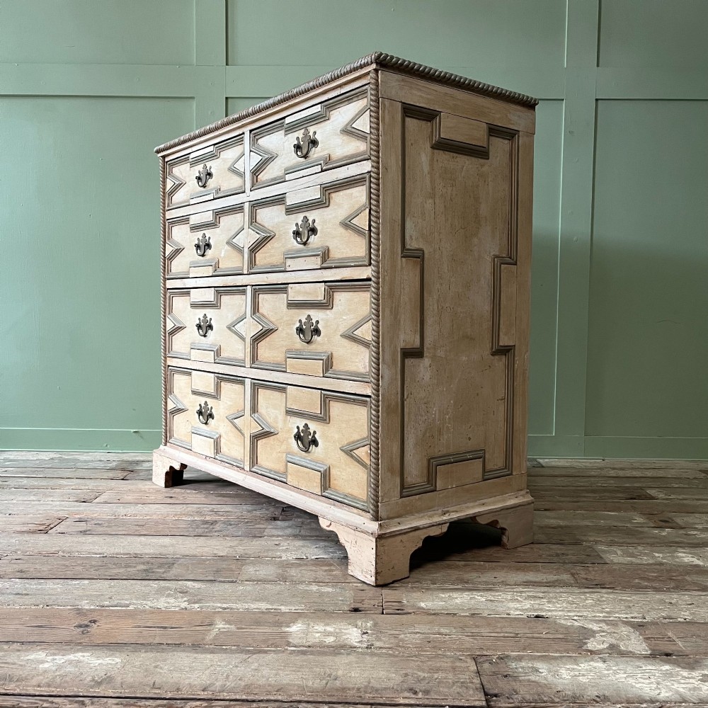An Edwardian painted chest of drawers featuring eight drawer fronts decorated with geometric panel mouldings, drop handles, and rope-twist edge detailing. View X