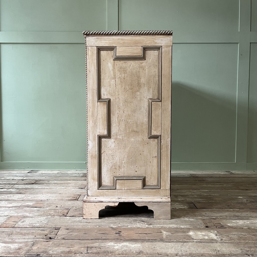 An Edwardian painted chest of drawers featuring eight drawer fronts decorated with geometric panel mouldings, drop handles, and rope-twist edge detailing. View XI