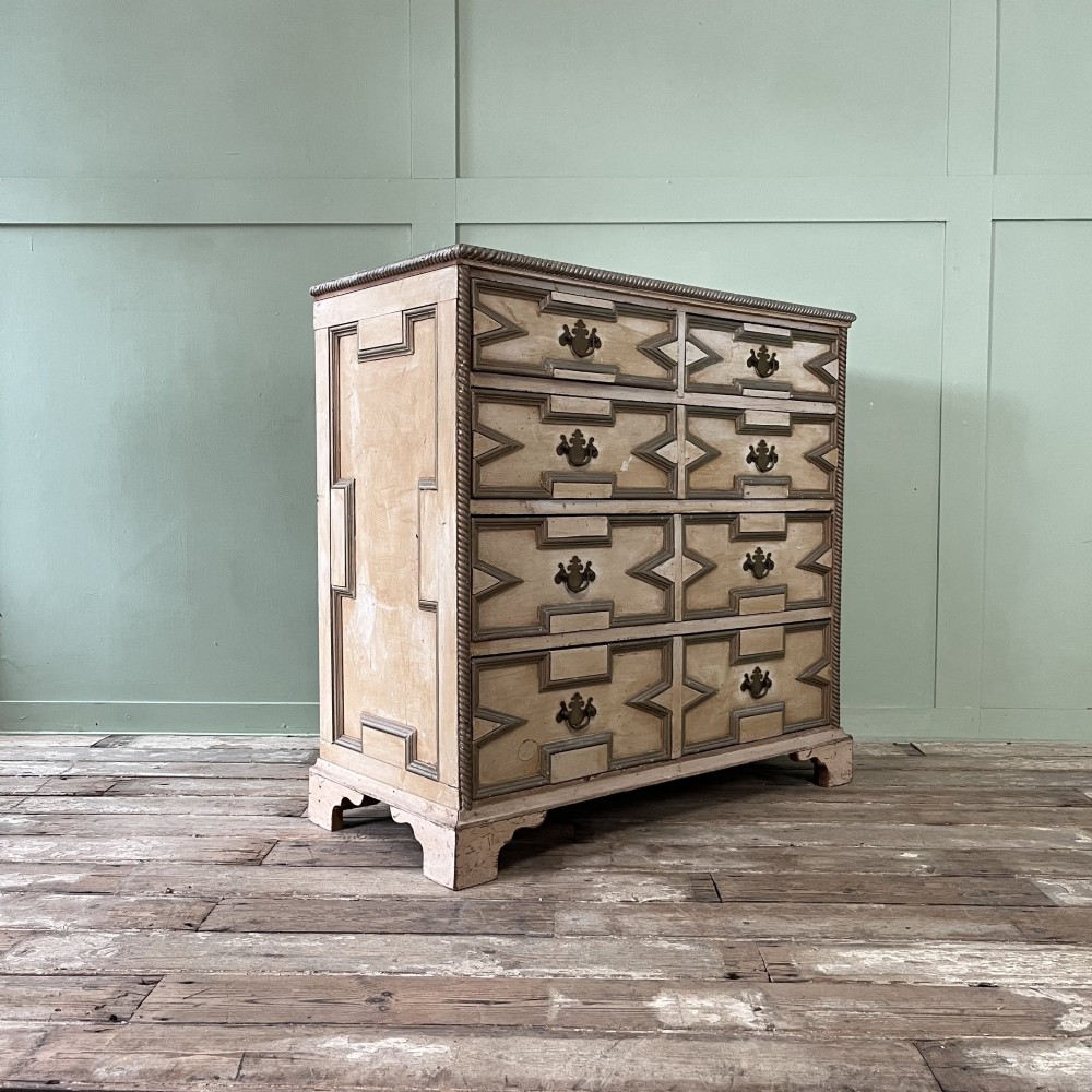An Edwardian painted chest of drawers featuring eight drawer fronts decorated with geometric panel mouldings, drop handles, and rope-twist edge detailing. View XII