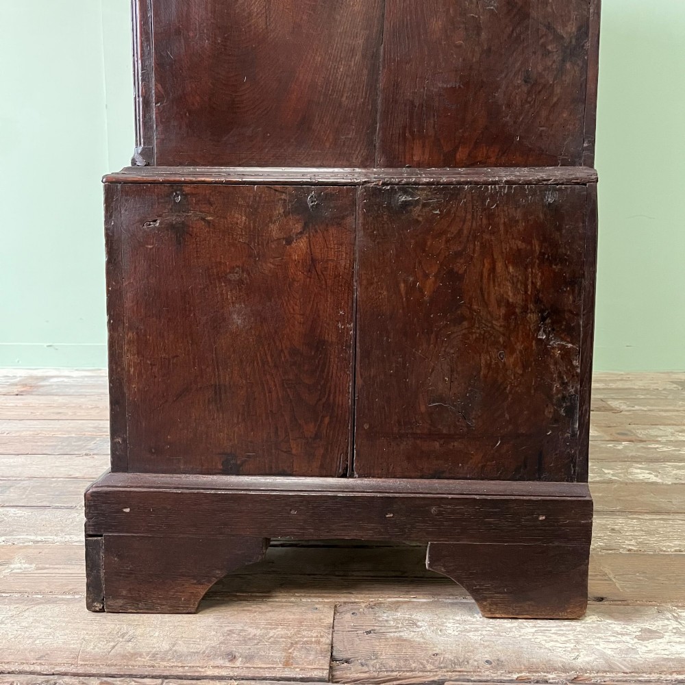 An 18th-century dark oak low linen press cupboard featuring arched fielded panel doors over a base with four drawers and brass handles. View IX